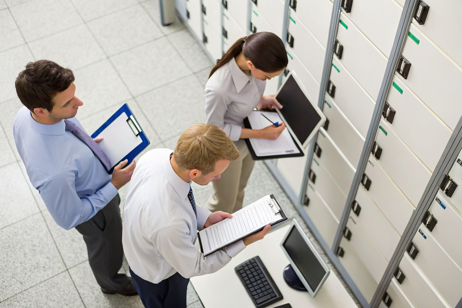 Personnel reviewing and documenting media devices in an office.